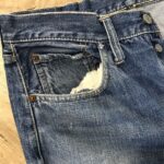 前ポケットの口が破れて、内側の白い袋布が見えているデニム